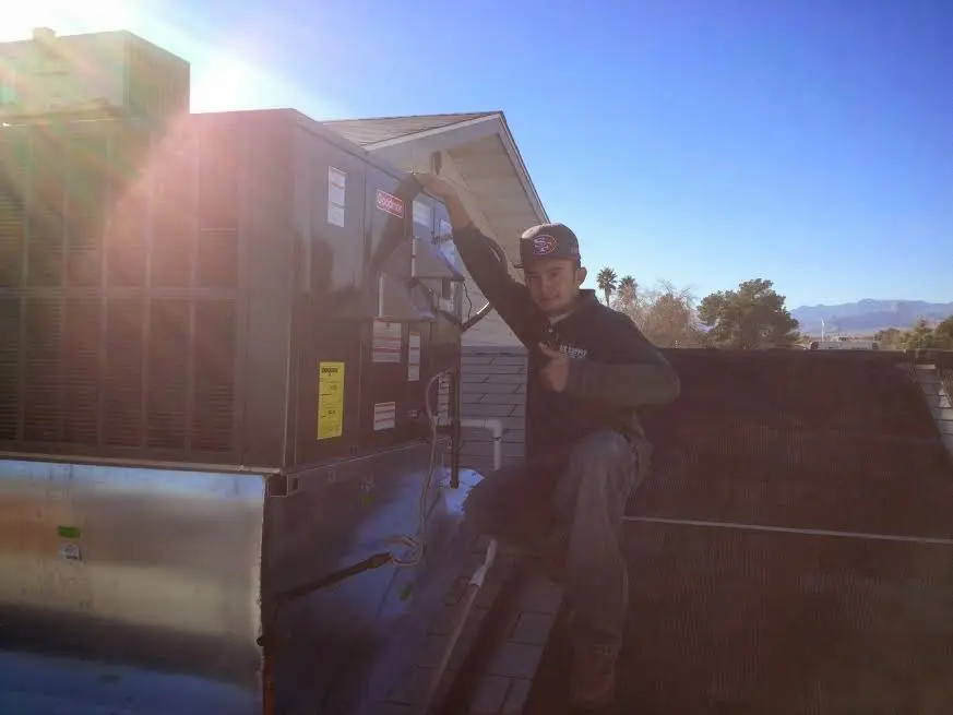 HVAC technician performing Heat Pump Repair on a rooftop unit in Hudsonville